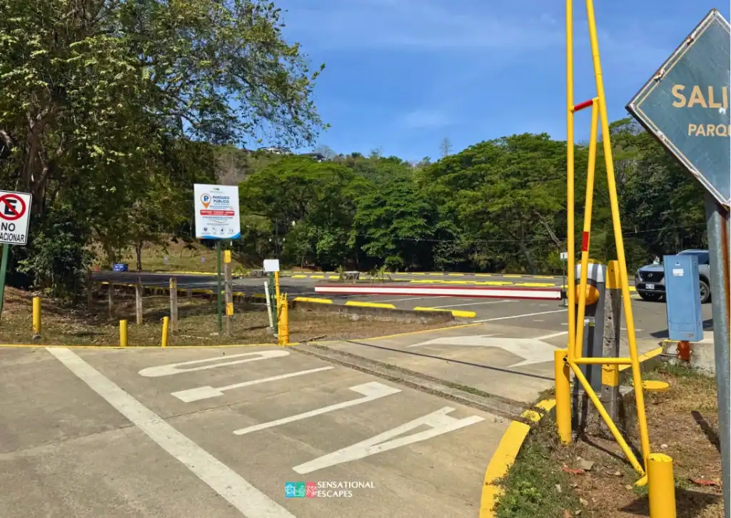 Entrance to a hotel-owned parking lot near Playa Blanca, featuring gated access, signage, and yellow-painted barriers surrounded by trees.