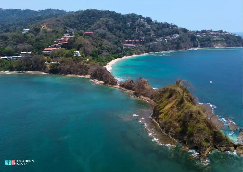 Aerial view of Playa Mantas and Playa Blanca in Puntarenas, Costa Rica, with turquoise waters, forested hills, and rocky islets in between.